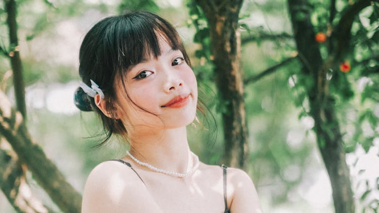 Smiling Young Woman With Blue Butterfly Hairpin Under A Tree