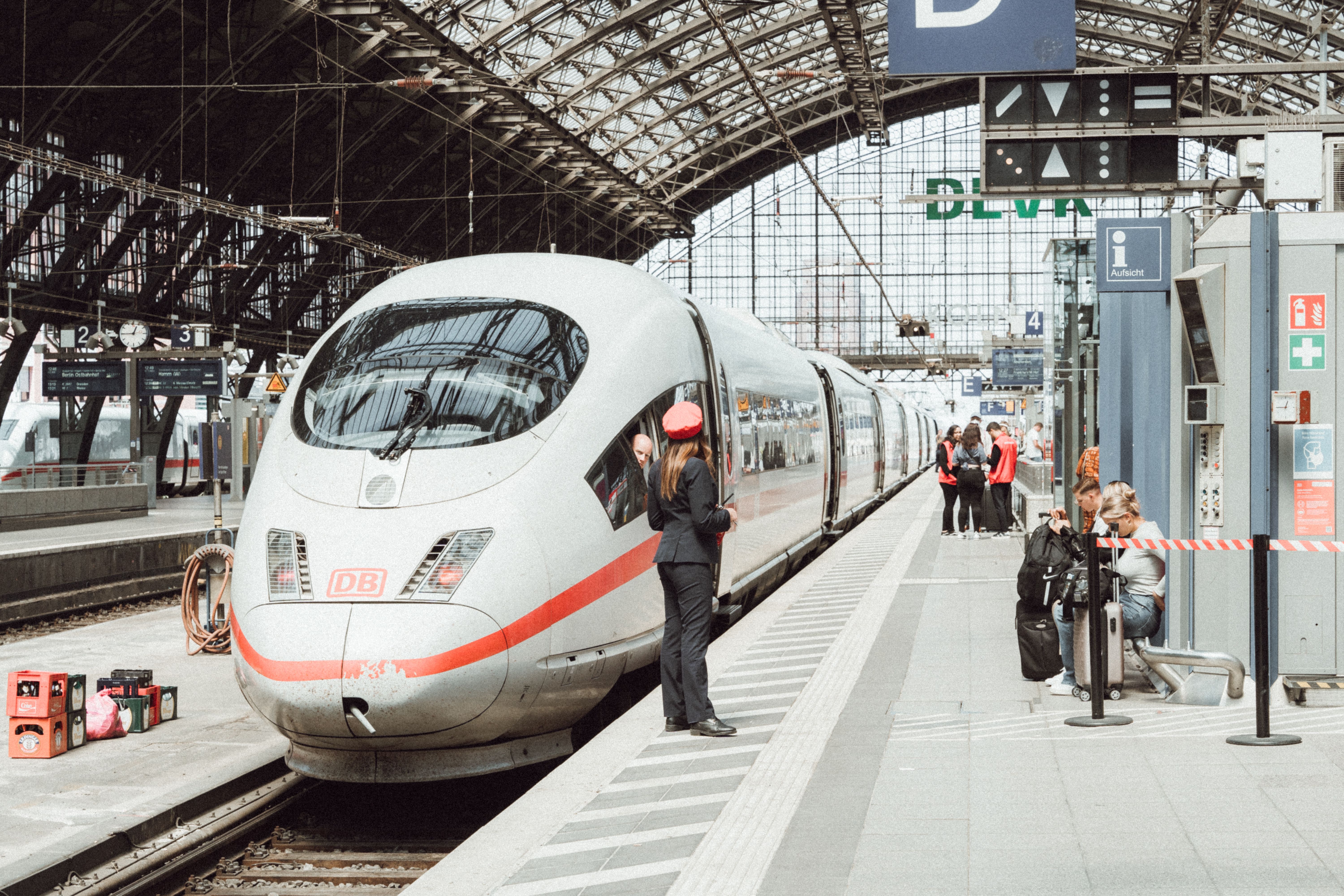 High-speed train stopped at a busy indoor station platform with passengers waiting nearby.