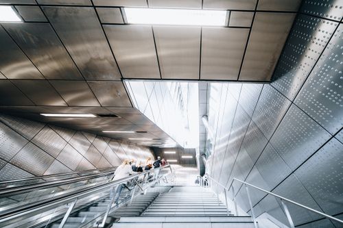 Free Low angle view of people on an escalator in a futuristic subway station with modern architectural design. Stock Photo