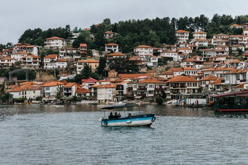 Free Picturesque view of a waterfront town with traditional houses and a fishing boat gliding across the water. Stock Photo