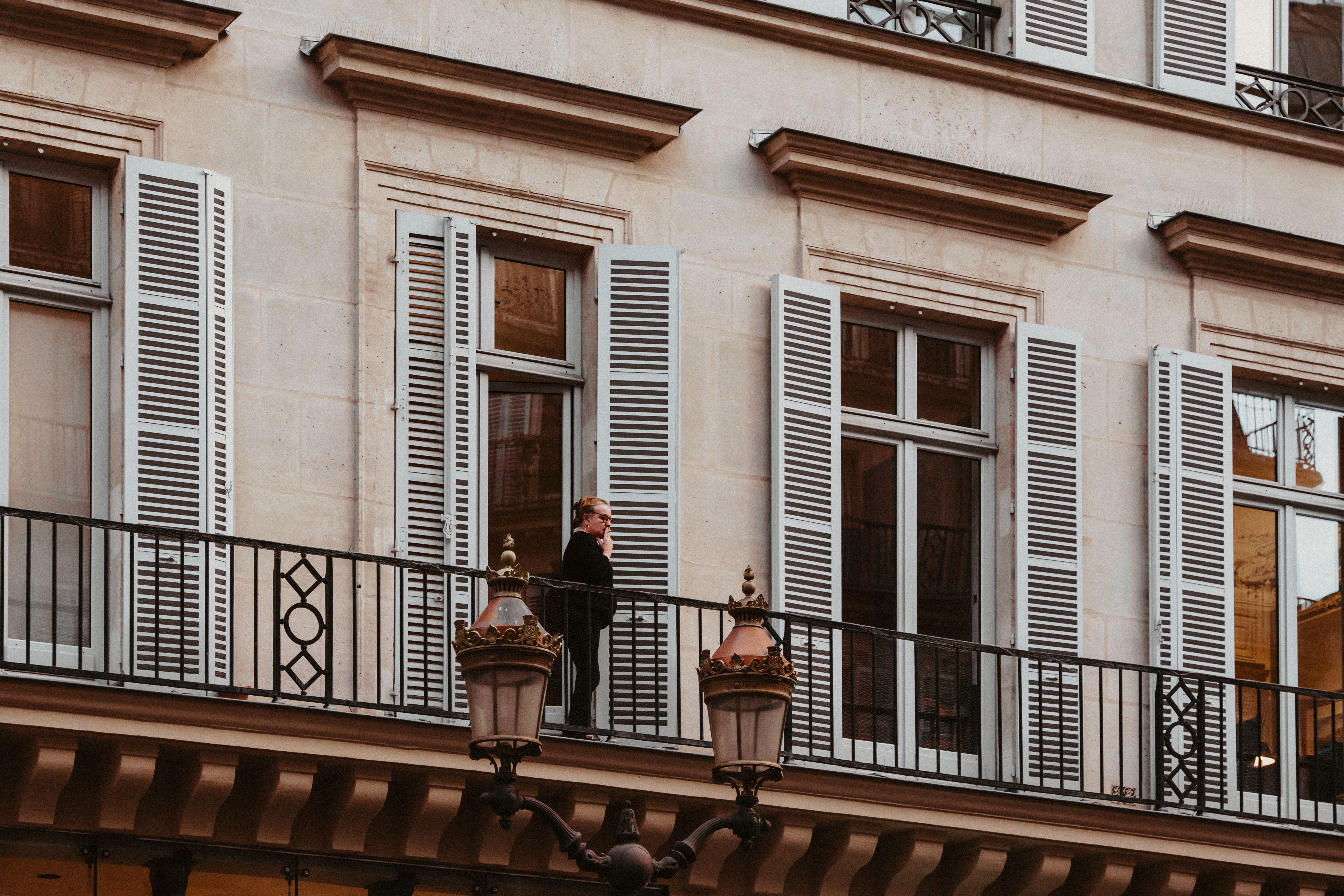 A woman stands on a sophisticated urban balcony, featuring elegant architectural design.