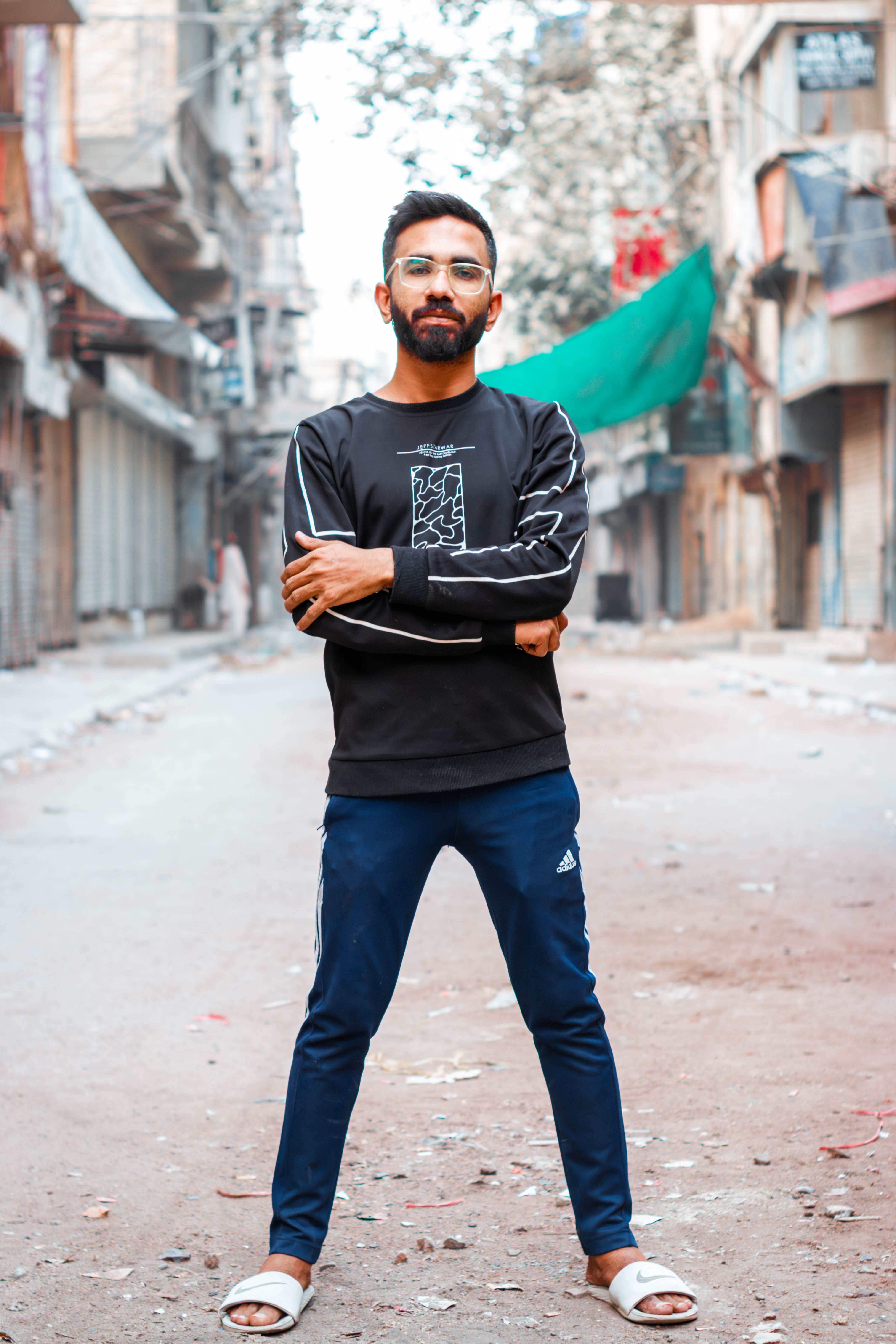 Stylish young man in casual outfit poses confidently on an urban street.