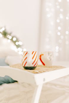 A cozy indoor scene with a bed tray featuring coffee mugs on a winter morning.