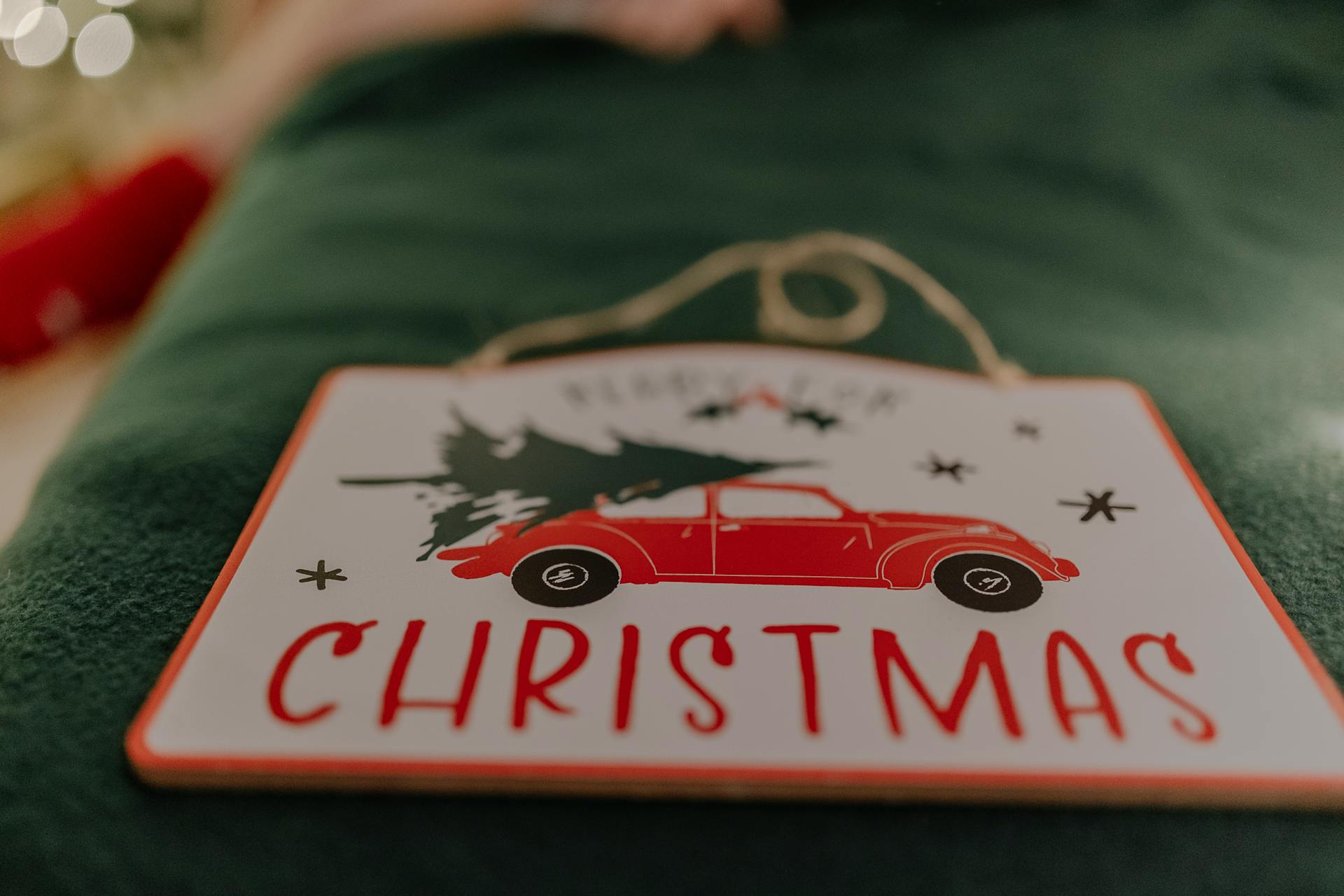 Close-up of a festive sign featuring a red car with a Christmas tree, creating holiday decor vibes.