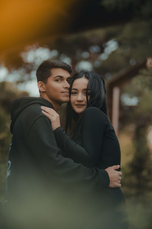 Free Romantic young couple hugging in a serene outdoor park setting, conveying warmth and affection. Stock Photo