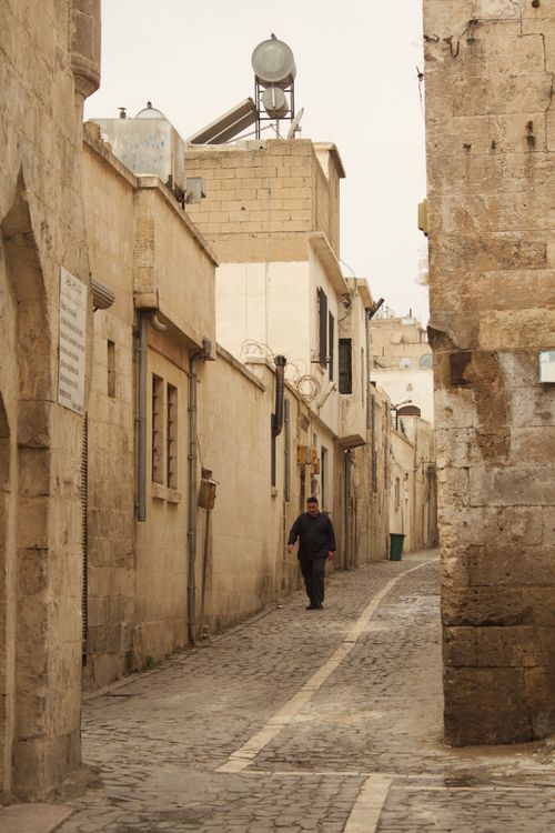 Free Man walking down a narrow, historic alley in Urfa, Turkey. Stock Photo