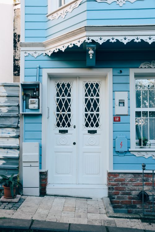 Free Charming blue house facade featuring white double doors with intricate lattice design. Stock Photo