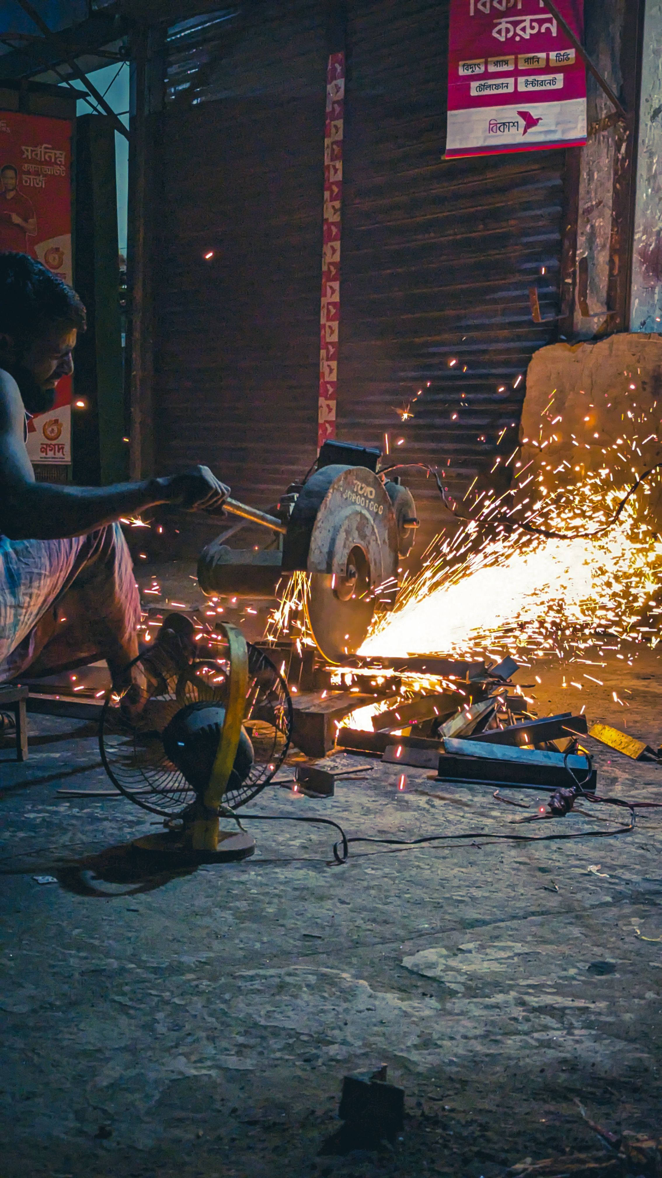 A man expertly welding metal, surrounded by sparks in an urban evening setting.