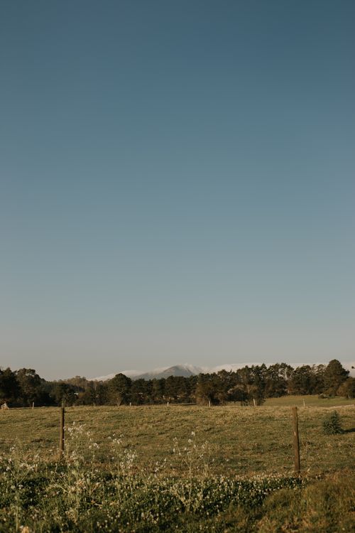 Free Peaceful rural landscape featuring a vast meadow and distant mountains under a clear sky. Stock Photo