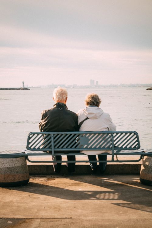 Free Senior couple enjoys a peaceful moment on a bench overlooking the sea. Stock Photo