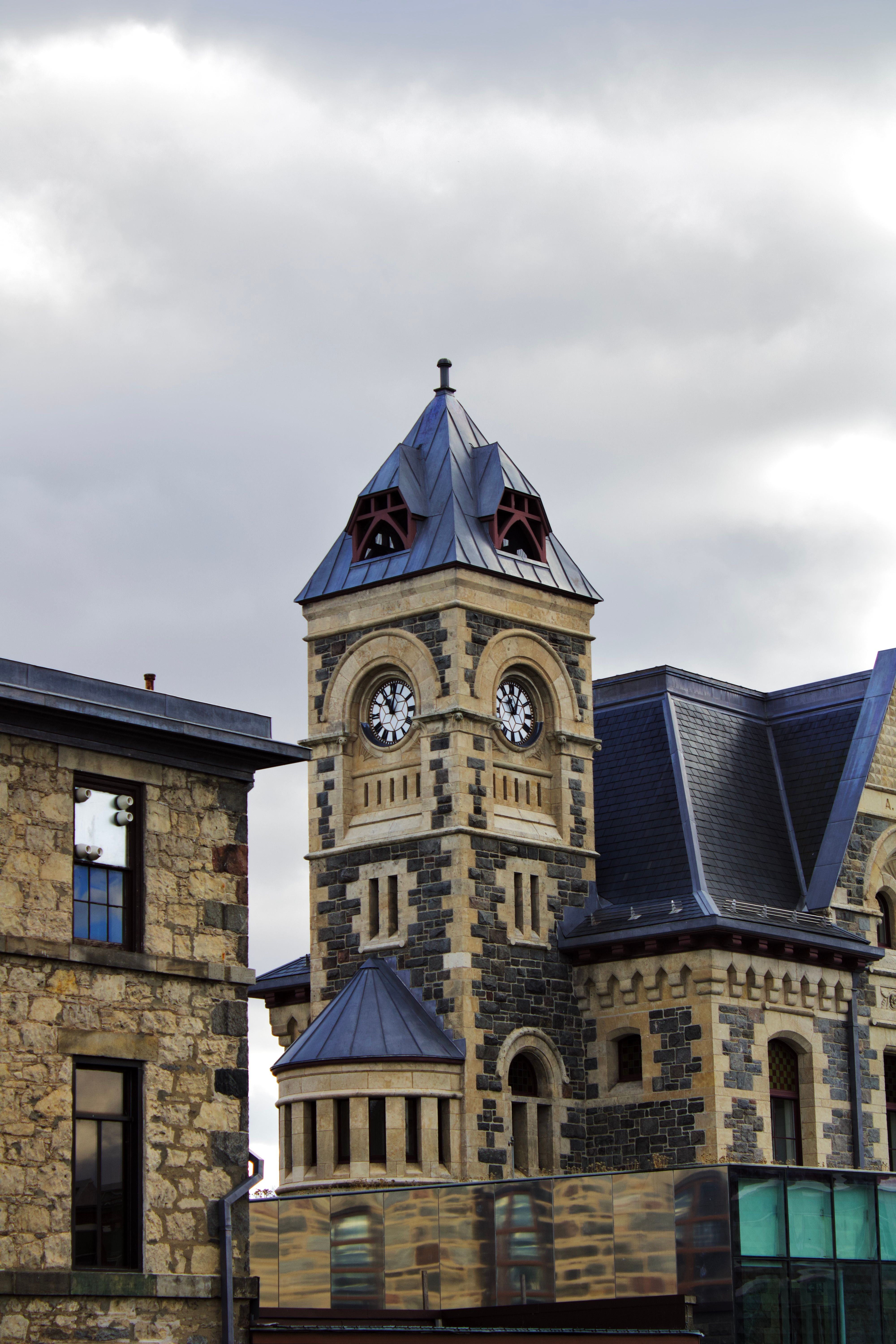 Stone Building with a Clock Tower and Blue Roofs · Free Stock Photo