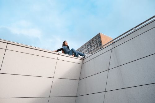 Free A stylish woman in denim sits on a rooftop corner in Berlin, exuding urban elegance. Stock Photo