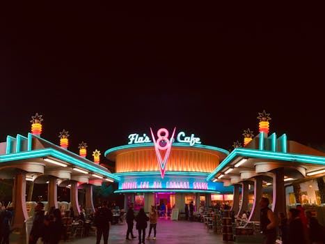 Vibrant neon lights illuminate Flo's V8 Cafe as visitors explore the lively nighttime atmosphere.