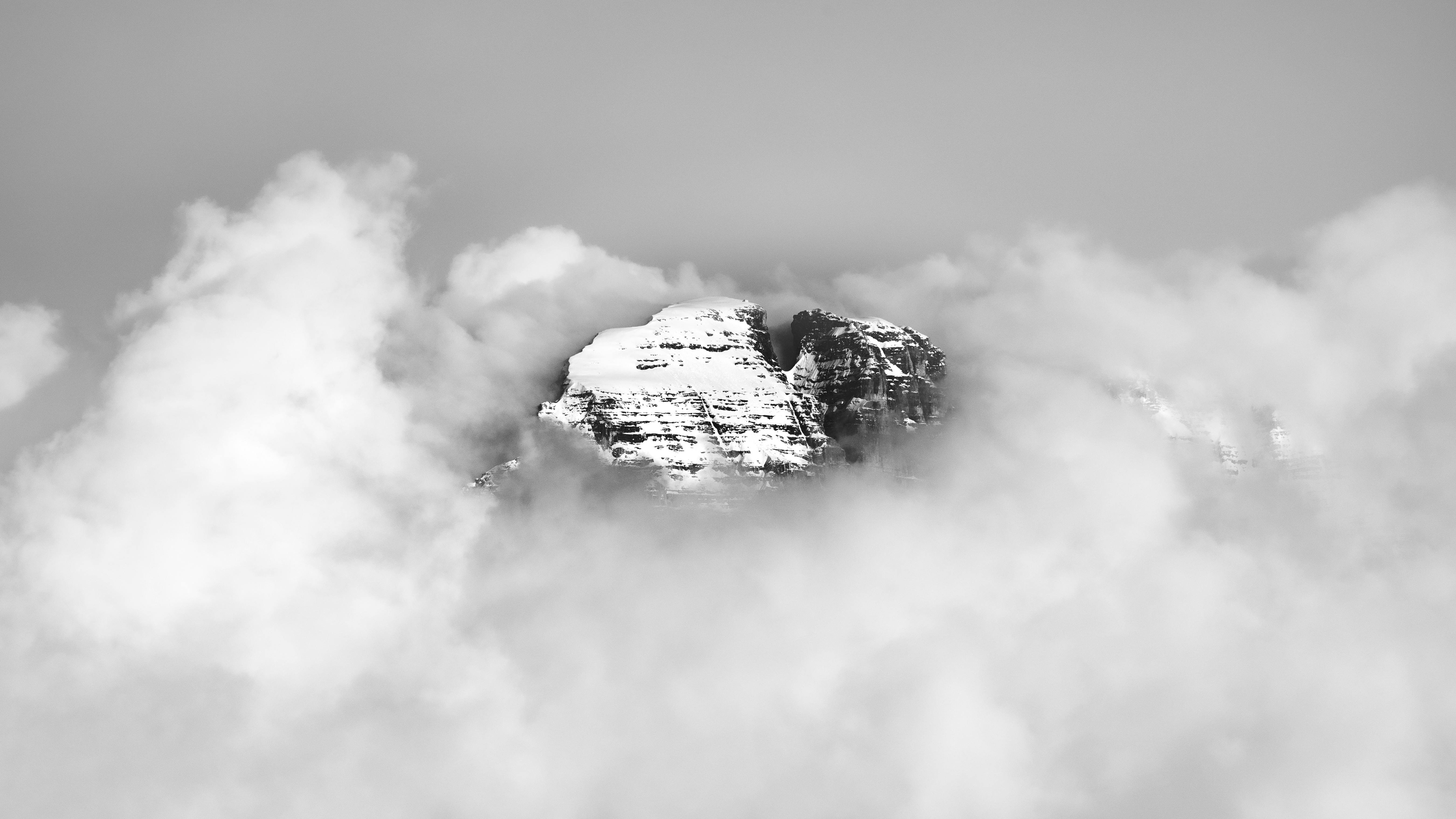 Prescription Goggle Inserts - A striking view of a snow-covered mountain peak surrounded by dense clouds, showcasing nature's beauty.