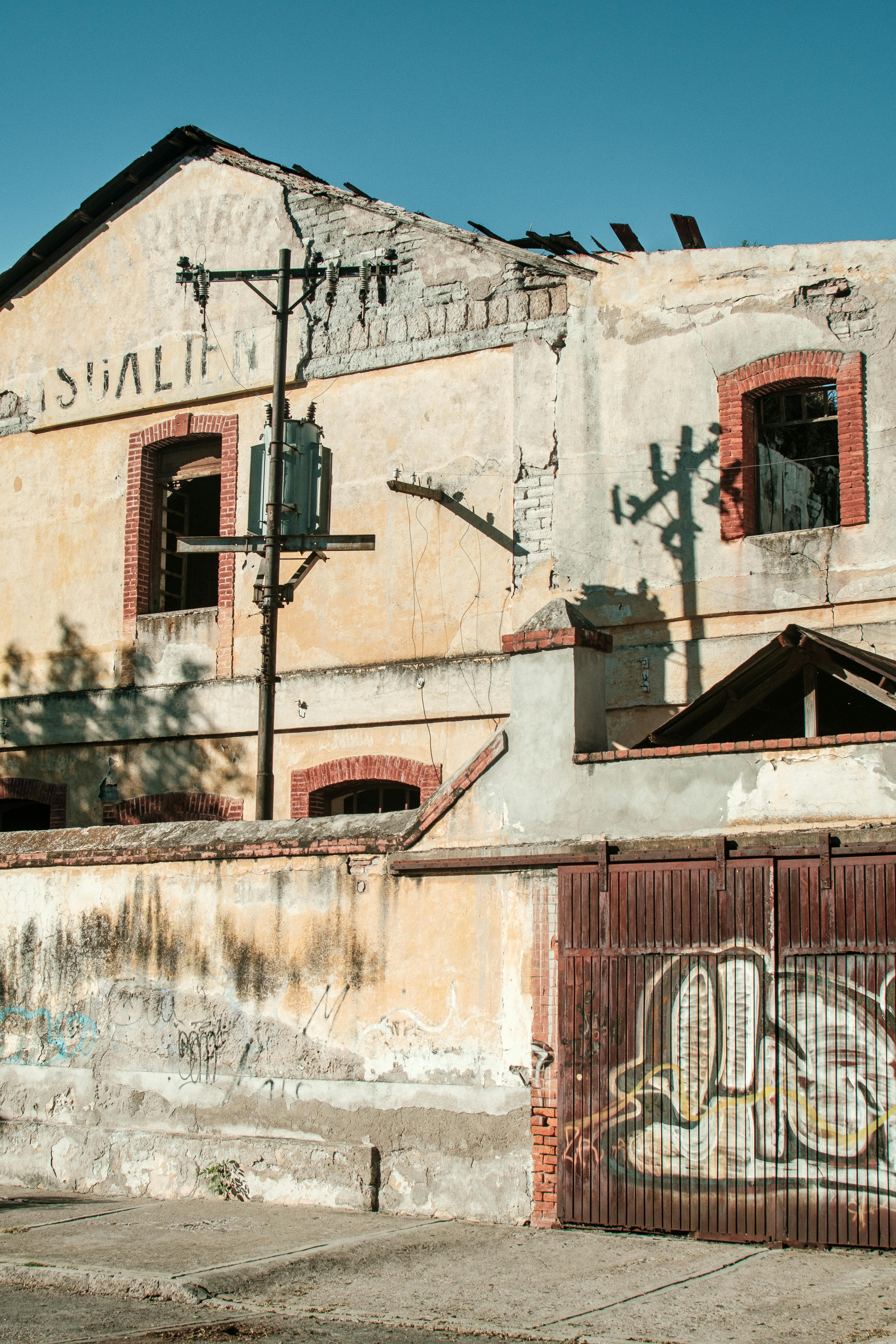 Decayed building with graffiti and urban aesthetic under blue skies.