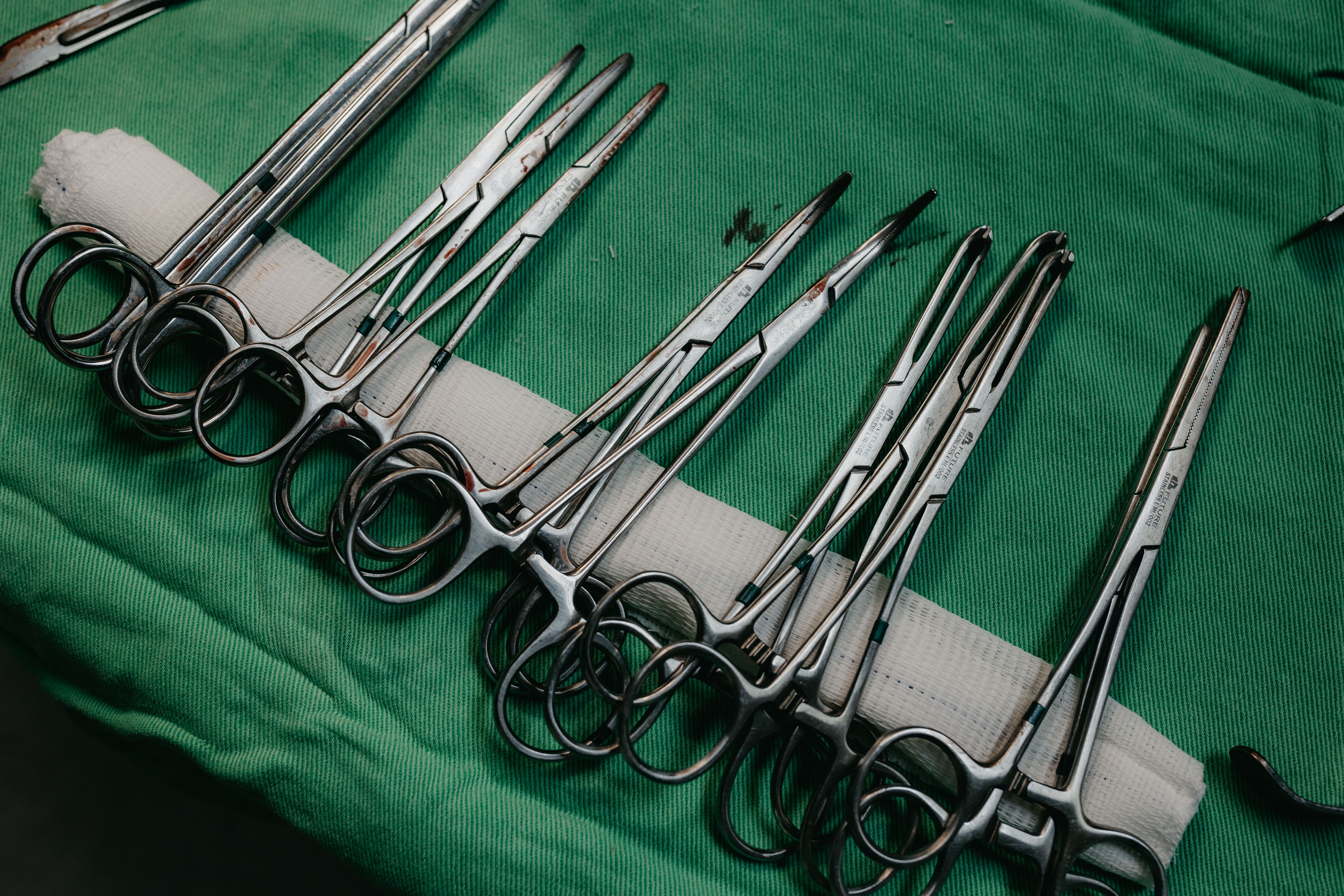 A set of surgical instruments neatly arranged on a green drape for medical procedures.