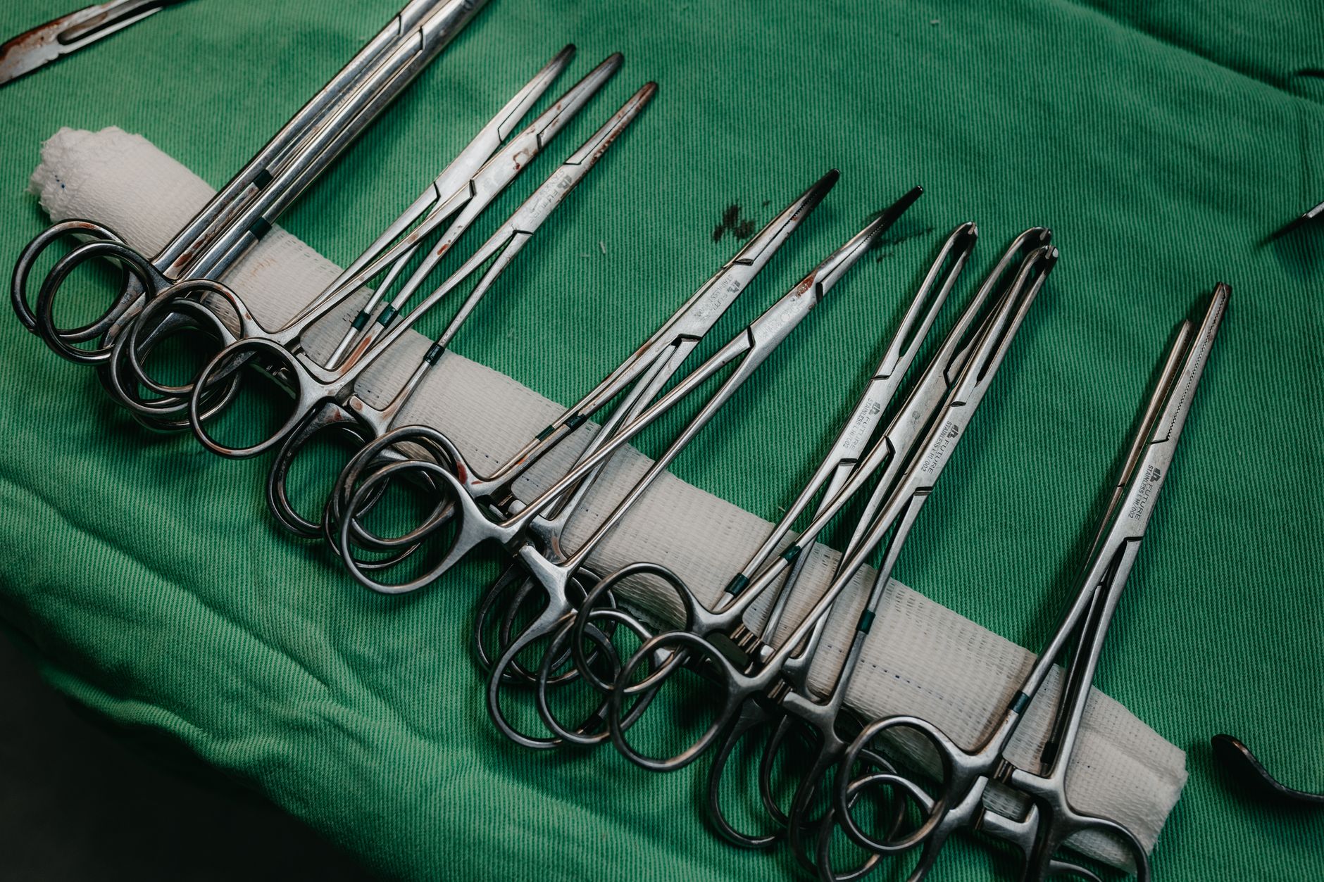 A set of surgical instruments neatly arranged on a green drape for medical procedures.