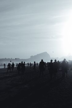 Beachgoers enjoy a sunset at Ipanema Beach with iconic Rio silhouette.