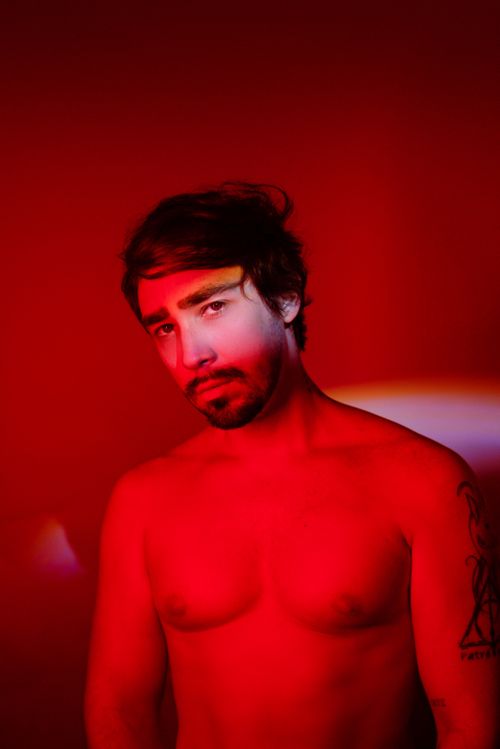 Free Dramatic artistic portrait of a shirtless man with beard under intense red lighting in studio. Stock Photo