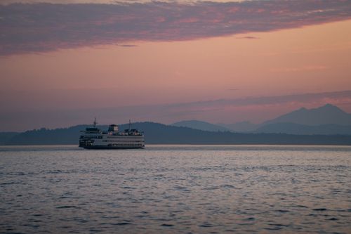 Free Scenic view of a ferry sailing at sunset with distant mountains near Seattle, WA. Stock Photo