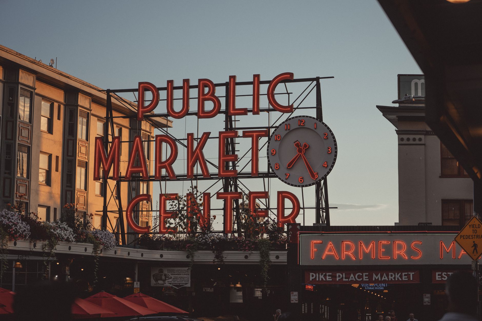 The famous Pike Place Market sign in Seattle captured during sunset with vibrant neon lights.