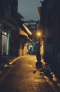 Explore a moody urban alleyway illuminated by a warm streetlamp at night, capturing the essence of quiet city streets.