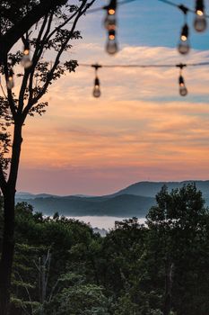 Idyllic sunset view of Blue Ridge Mountains with glowing lanterns and misty landscape.