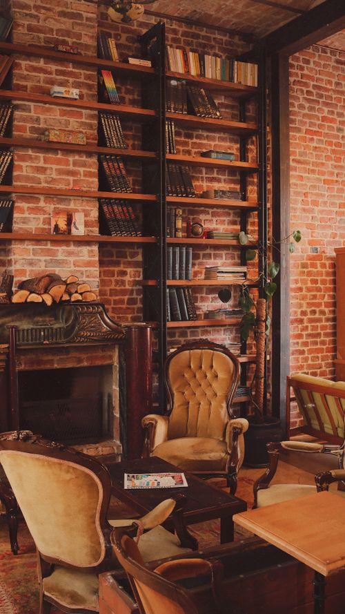 Free Luxurious library interior featuring brick walls, armchairs, and an elegant fireplace. Stock Photo