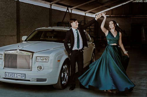 Elegant Couple Posing by a White Rolls-Royce Phantom Car