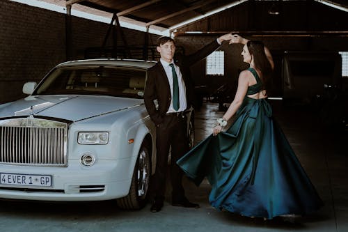 Elegant Man and Woman Posing by a White Rolls-Royce Phantom Car