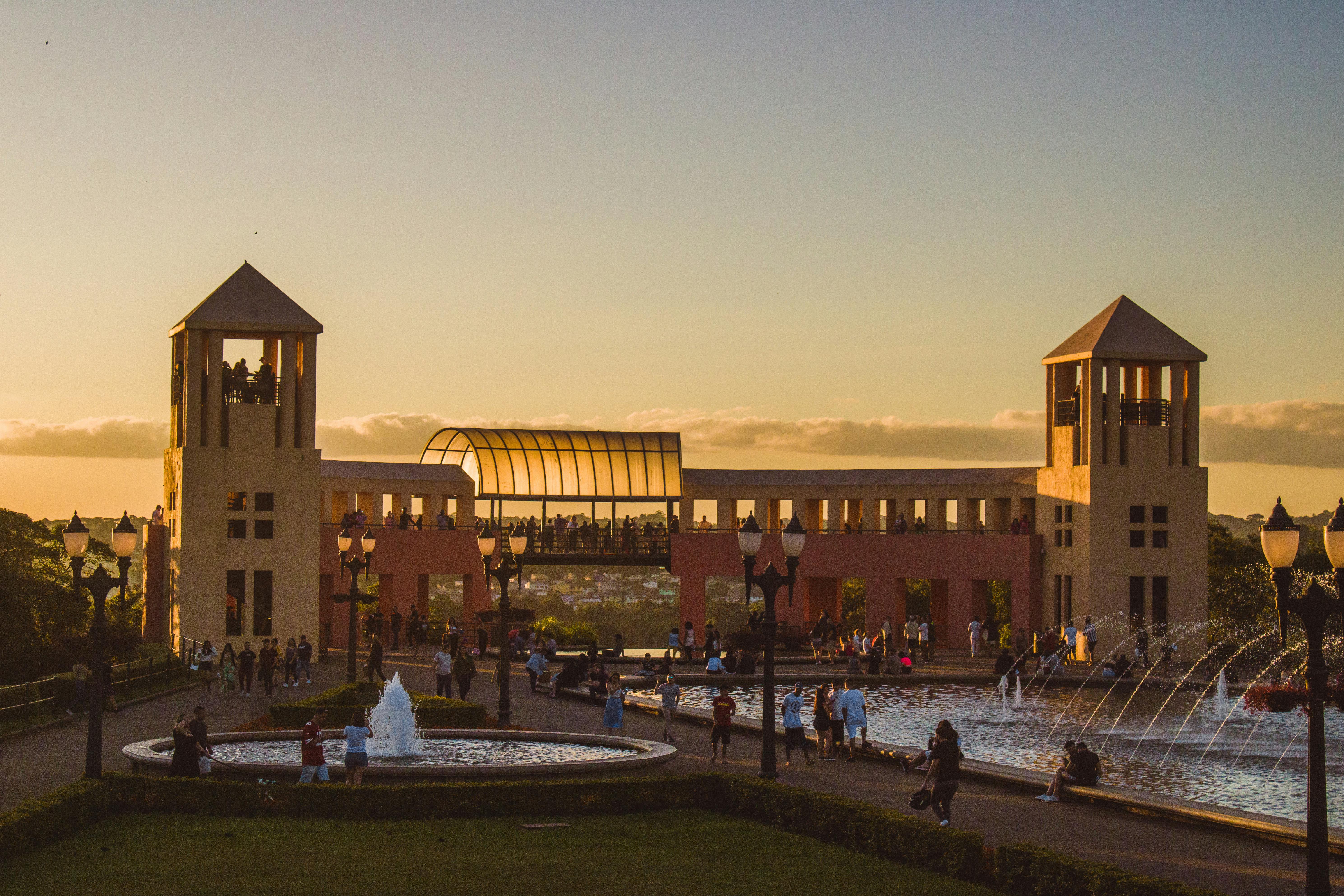 Scenic view of Parque Tanguá at sunset with fountains and a crowd in Curitiba, Brazil.