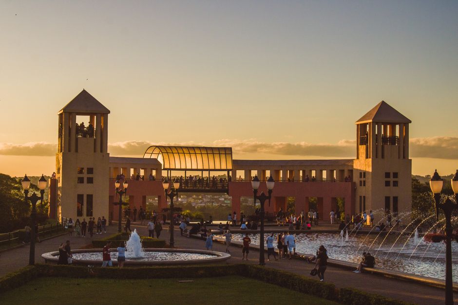 Scenic view of Parque Tanguá at sunset with fountains and a crowd in Curitiba, Brazil.