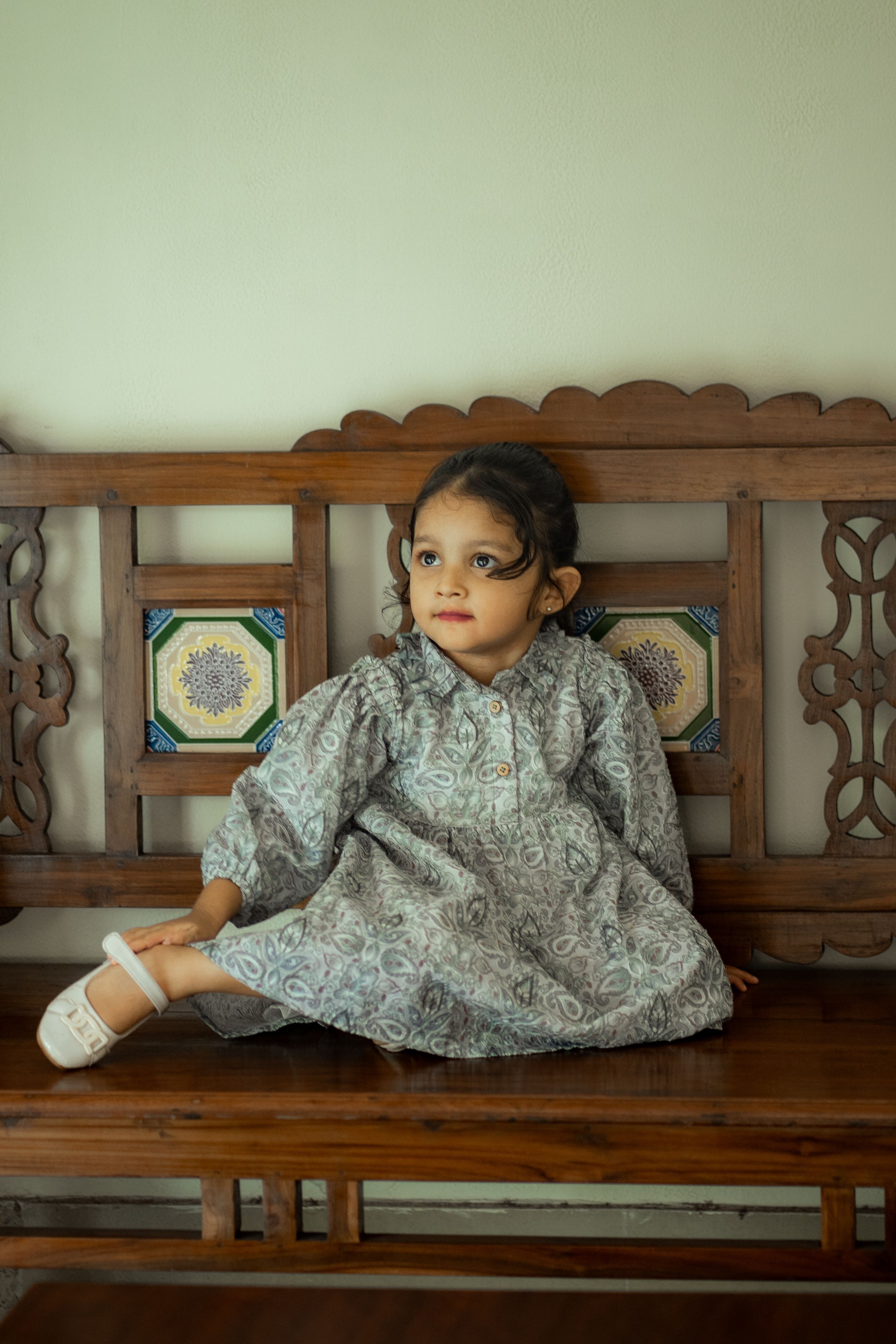Little Girl in a Gray Dress Sitting on a Wooden Bench · Free Stock Photo