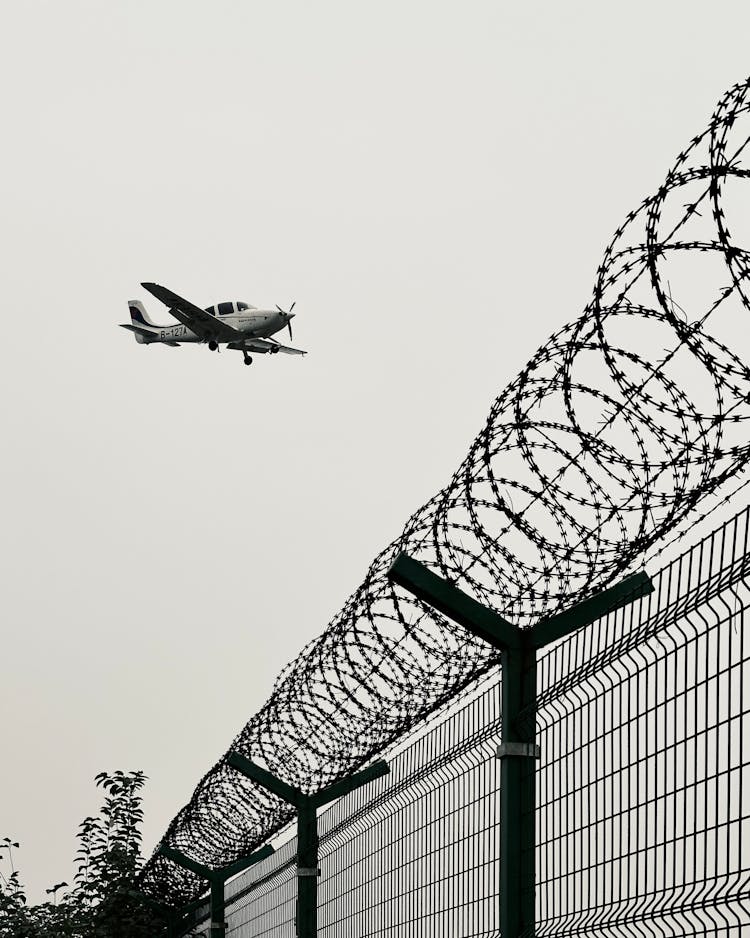 Small Single-Engine Plane Cirrus SR22 Flying Over The Airport Fence