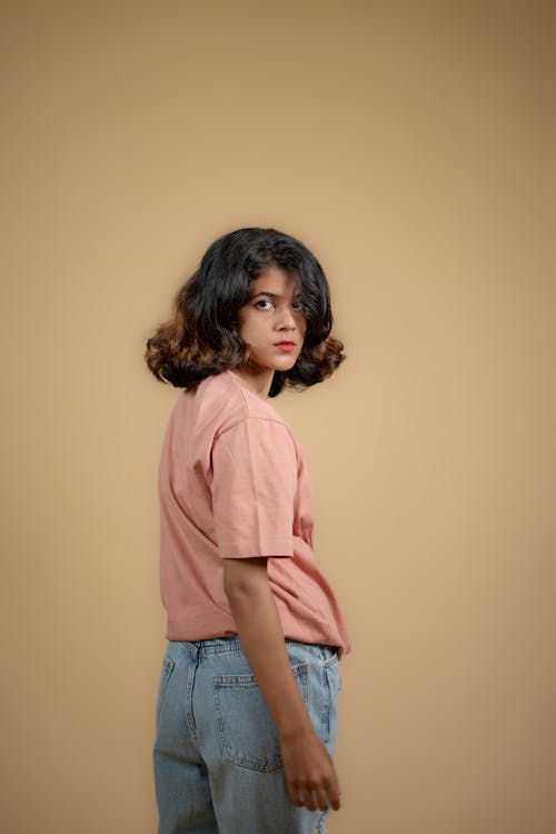 Young Model in a Pink T-shirt and Jeans Looking over Her Shoulder