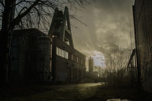 Free Moody sunset view of an abandoned industrial facility with dramatic clouds. Stock Photo