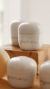 Minimalist white cosmetic jars on a wooden platform, perfect for skincare branding.