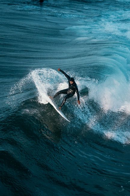 A surfer in a wetsuit skillfully rides a wave, showcasing dynamic water sports action.