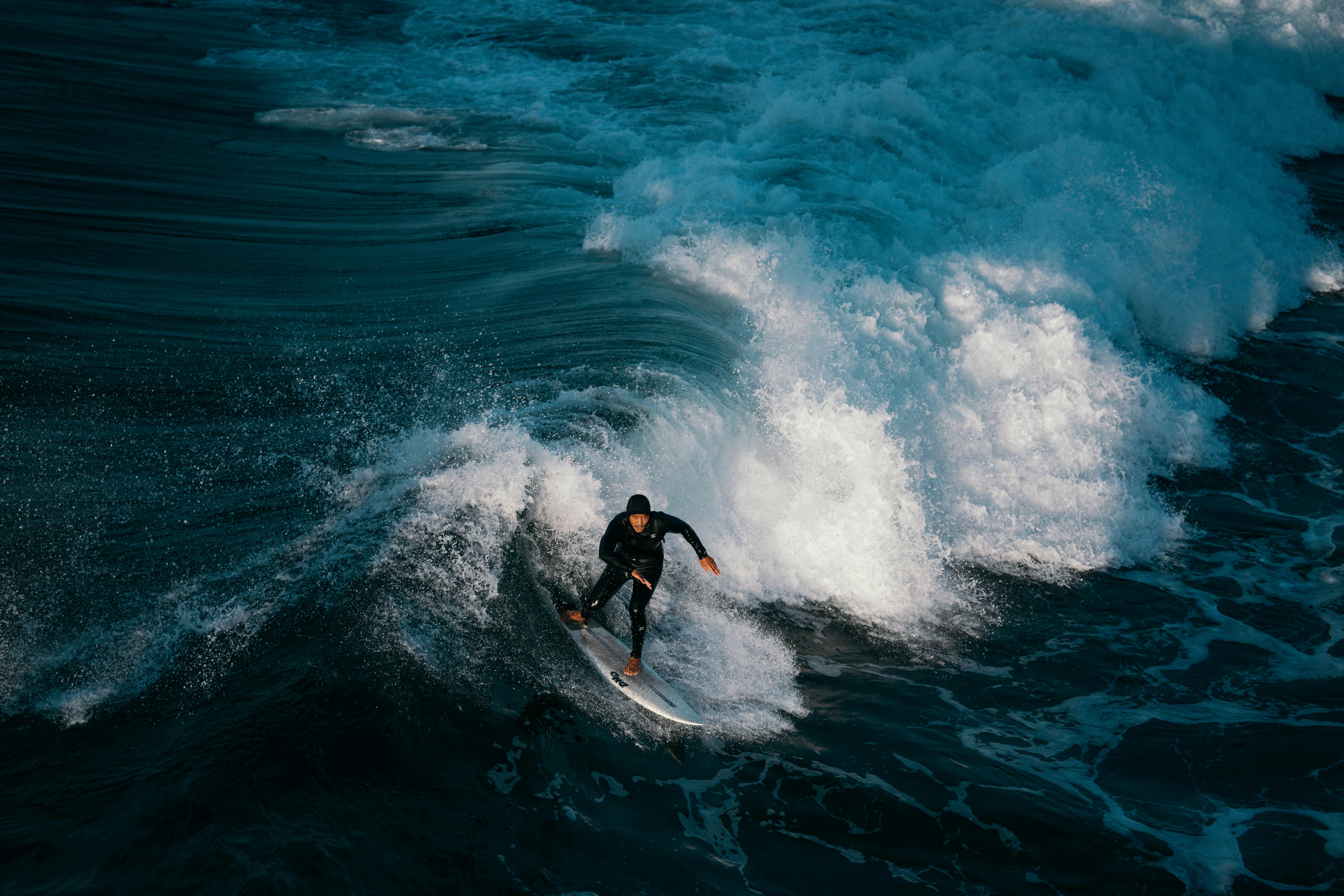 Surfer riding ocean waves in a wetsuit, showcasing dynamic motion and thrilling sport energy.