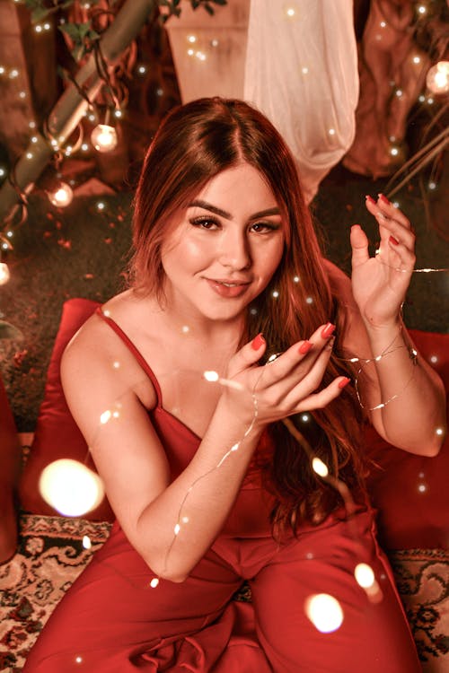 Red-haired Woman in Red Clothes Hanging Christmas Lights Sitting on the Carpet