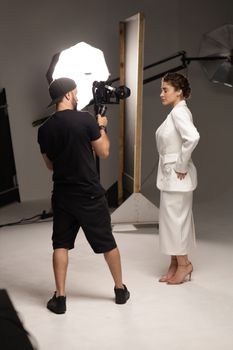 Fashion photoshoot with model and photographer in a studio setting.
