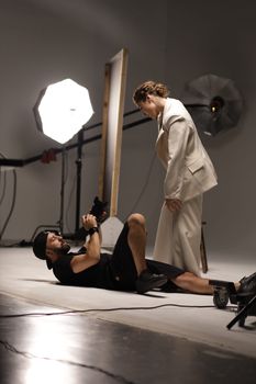 Contemporary studio shoot featuring a photographer capturing a model in elegant attire.