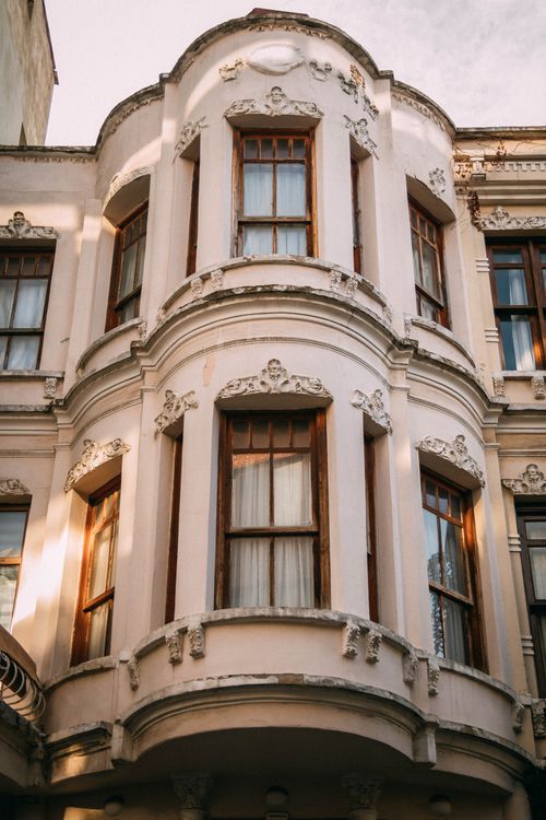 Free Elegant facade of an old urban building featuring ornate bay windows and classic architectural details. Stock Photo
