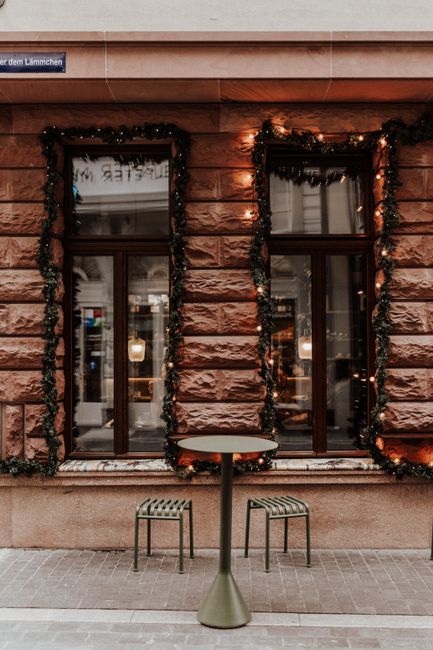 A festive city street view with decorated building facade and chairs.