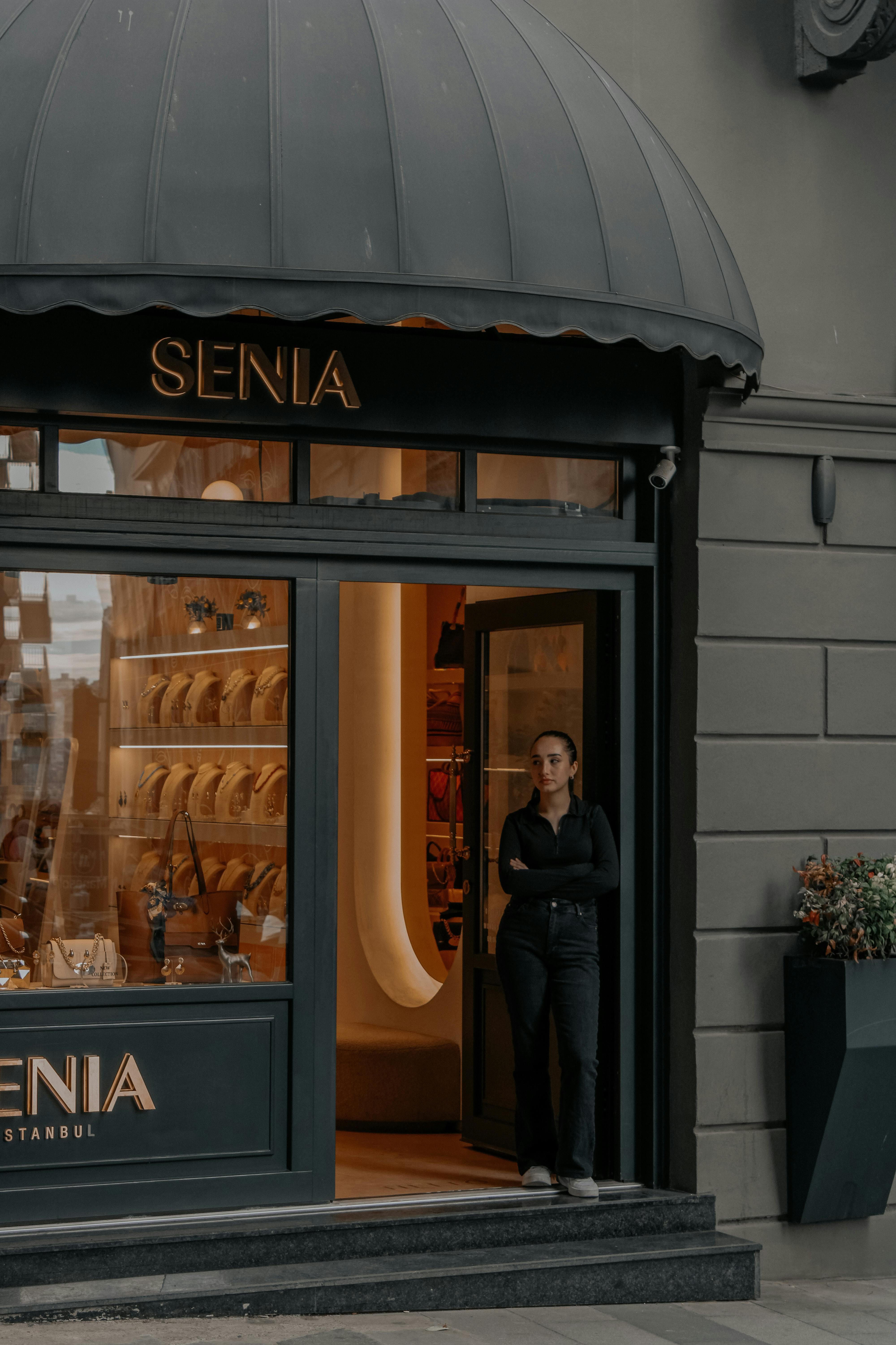 A woman stands at the entrance of a fashion store in the city, showing urban style.