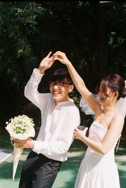 Happy newlywed couple dancing joyfully in a summer outdoor setting.