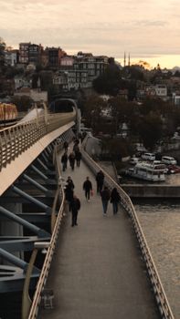People walking on a footbridge in Istanbul during sunset, capturing the lively urban atmosphere.