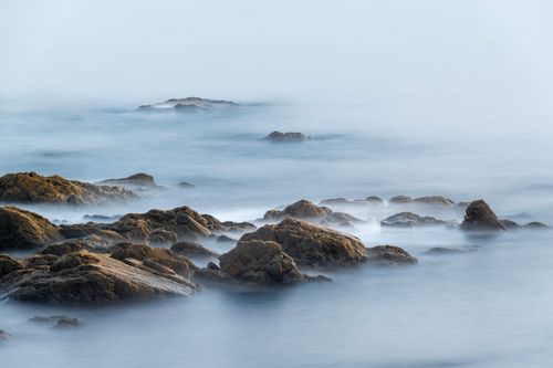 Free Serene seascape featuring misty waves flowing over coastal rocks, capturing nature's tranquility. Stock Photo