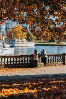 A man and woman enjoying autumn views by the water in Vancouver's urban marina.