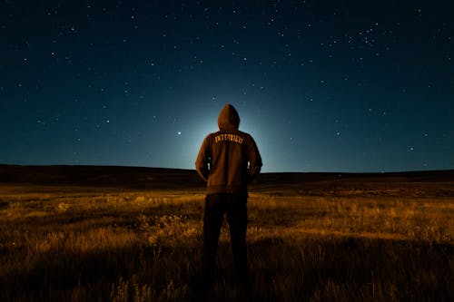 Man in Hoodie on Grassland at Night